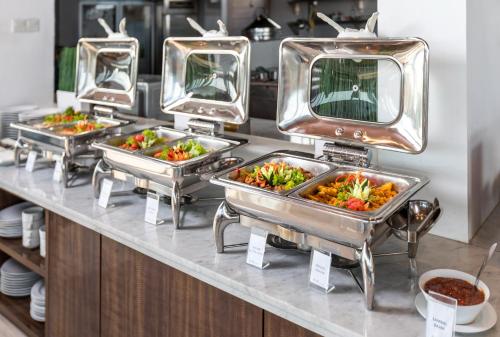 Una línea de buffet con tres bandejas de comida. en Boss Legian Hotel Powered by Archipelago, en Legian
