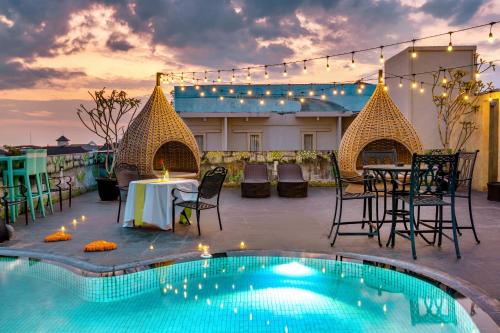 een patio met een tafel en stoelen naast een zwembad bij Boss Legian Hotel Powered by Archipelago in Legian