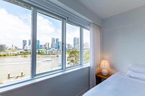 een slaapkamer met een groot raam met uitzicht op de stad bij Riverside 2 Bedroom apartment with parking in Brisbane