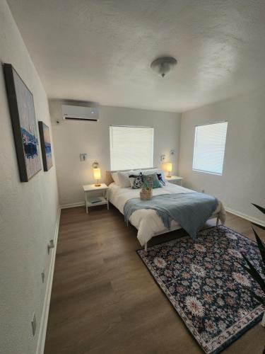 a bedroom with a bed with a rug and two windows at Hostel Beds & Sheets FLL AIRPORT in Dania Beach