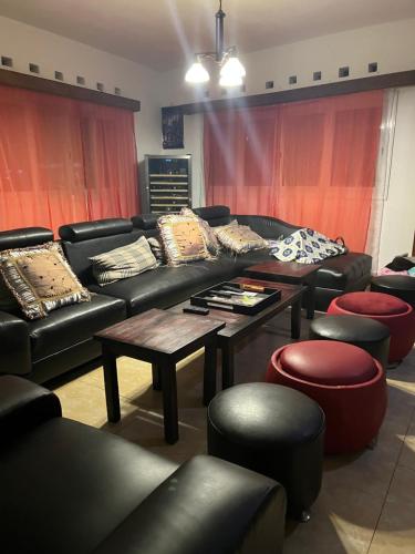 a living room with black couches and red curtains at Villa CALLI in Sambava