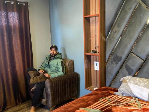 un hombre sentado en una silla en un dormitorio en Home sleeper en Srinagar