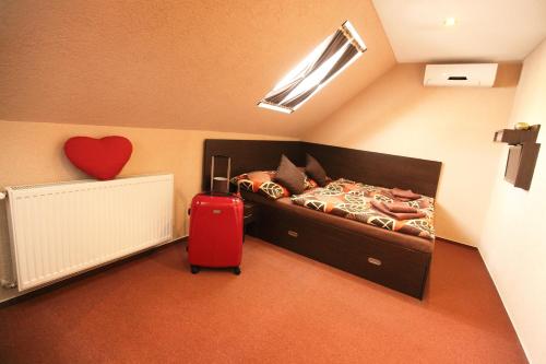 1 dormitorio con 1 cama y 1 maleta roja en Penzion Škorpión, en Senec