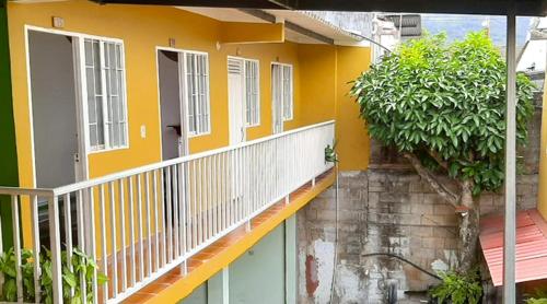 a yellow building with a balcony with plants on it at LA AVENIDA ALOJAMIENTO in Guaduas