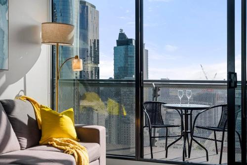 a living room with a couch and a table on a balcony at Breathtaking View - 2BR Apt in Melbourne CBD w Gym in Melbourne
