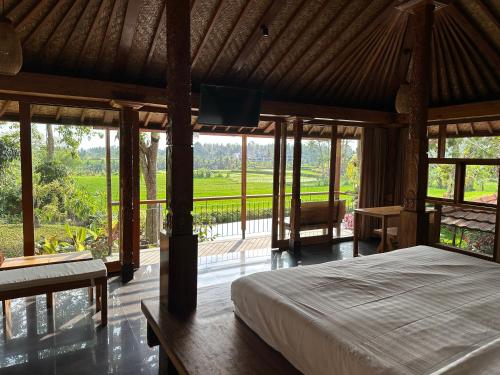 a bedroom with a bed and a large window at GRIYA KCB VILLA in Ubud