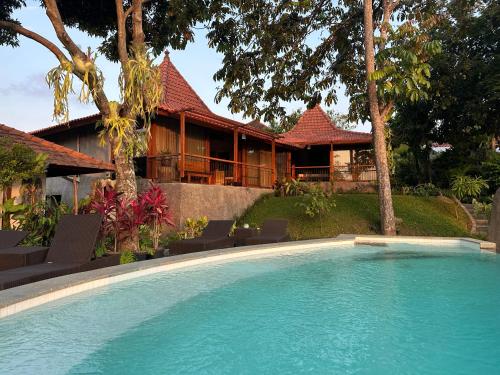 a swimming pool in front of a house at GRIYA KCB VILLA in Ubud
