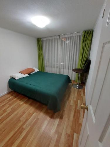 1 dormitorio con cama verde y suelo de madera en Edificio Plaza Las Palmas 1006, en Iquique