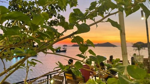 a tree with a view of the water with a boat at Le Pont Bungalow Cat Ba in Cat Ba