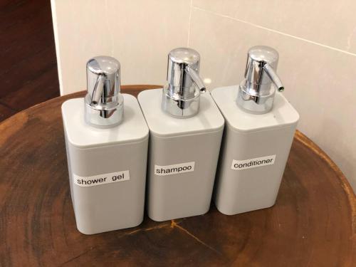 two white soap dispensers sitting on a wooden table at Turi Beach Resort in Nongsa