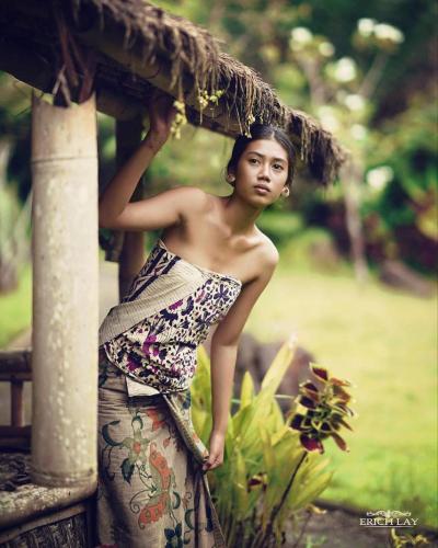 a young man in a dress sitting on a porch at Sun Sang Eco Retreats in Tabanan