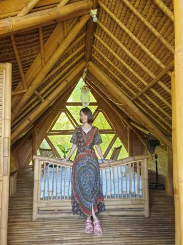 a woman is standing on a wooden bridge at Sun Sang Eco Retreats in Tabanan