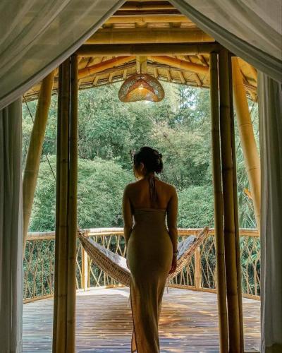 a woman in a gold dress standing on a bridge at Sun Sang Eco Retreats in Tabanan