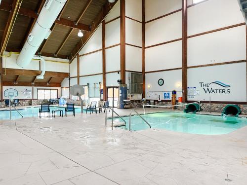 een zwembad in een groot gebouw met stoelen en tafels bij The Waters of Minocqua in Minocqua