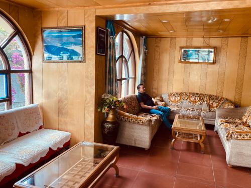 un hombre sentado en un sofá en una sala de trenes en Sandhu Farm House en Chandigarh