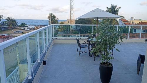 卡博迪聖阿戈斯蒂尼奧的住宿－Lindo apartamento pé na areia em Cabo Gaibú prox Porto de galinhas，阳台配有桌子、植物和雨伞。
