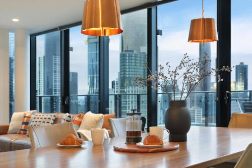 a dining room table with a view of a city at The Canvas Apartment Hotel in Melbourne