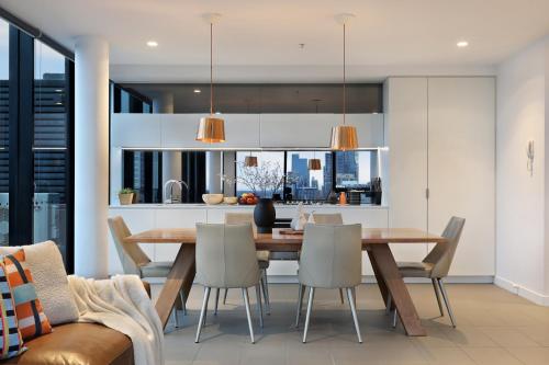 a kitchen and dining room with a wooden table and chairs at The Canvas Apartment Hotel in Melbourne