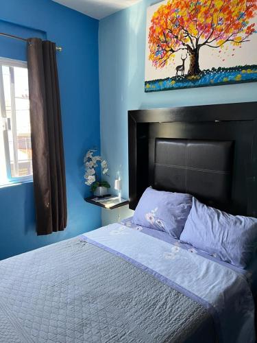 a bedroom with a bed with a tree painting on the wall at Estancia María Bonita Morelia in Morelia