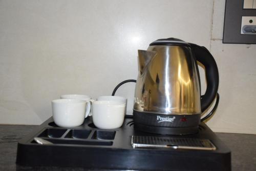 a coffee pot sitting on top of a stove with three cups at 2BHK luxury Escape in rishikesh in Rishīkesh