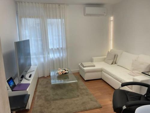 een woonkamer met een witte bank en een tv bij Precioso, barrio Magdalena in Ferrol