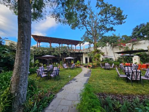 a group of chairs and tables in a garden at Hotel Casa Bansley in Antigua Guatemala