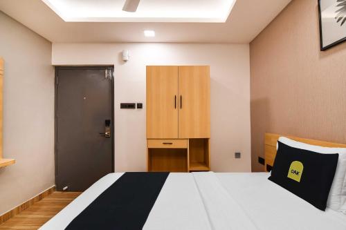 a bedroom with a bed and a cabinet and a door at Super Townhouse OAK Sayhallo Ecstasy in Bhubaneshwar
