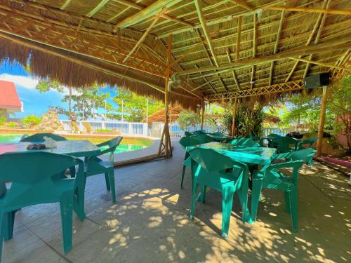 a restaurant with green tables and chairs under a roof at AoJing Diving Resort澳鲸潜水温泉店 in Dauin