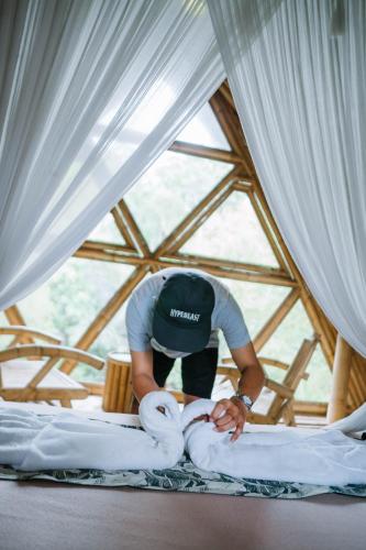 a man placing blankets on a bed in a tent at Sun Sang Eco Retreats in Tabanan