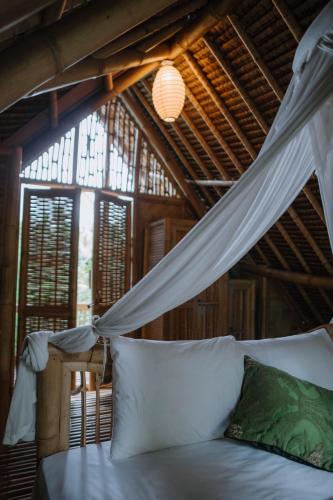 a bedroom with a bed with a mosquito net at Sun Sang Eco Retreats in Tabanan