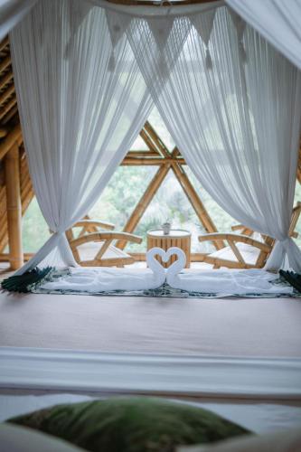 a bed in a room with white curtains at Sun Sang Eco Retreats in Tabanan