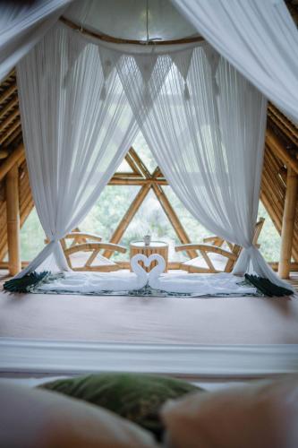 a bed in a room with a window with a white canopy at Sun Sang Eco Retreats in Tabanan