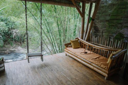a porch with a couch in the middle of a forest at Sun Sang Eco Retreats in Tabanan