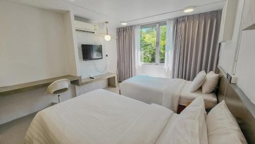 a hotel room with two beds and a television at R1 Nimman Hotel Chiangmai in Chiang Mai