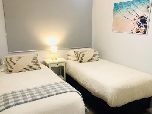 two beds in a room with a lamp on a table at API Middleton Beach Front Apartments Albany in Albany