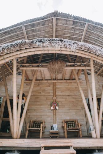 a building with two chairs and a straw roof at Sun Sang Eco Retreats in Tabanan