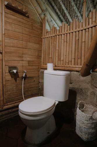 a bathroom with a toilet in a wooden room at Sun Sang Eco Retreats in Tabanan