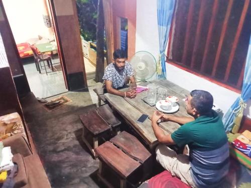 two men sitting at a wooden table in a room at Kandy Col Holiday Resort in Kandy