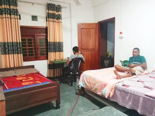 two men sitting in a room with a bed and a desk at Kandy Col Holiday Resort in Kandy