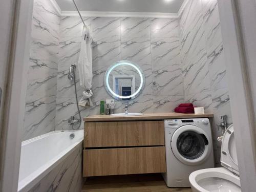 ein Badezimmer mit Waschbecken und Waschmaschine in der Unterkunft Уютные апартаменты в элитном комплексе in Almaty