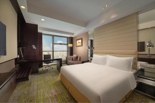 a bedroom with a large white bed and a desk at Holiday Inn Beijing Focus Square by IHG in Beijing