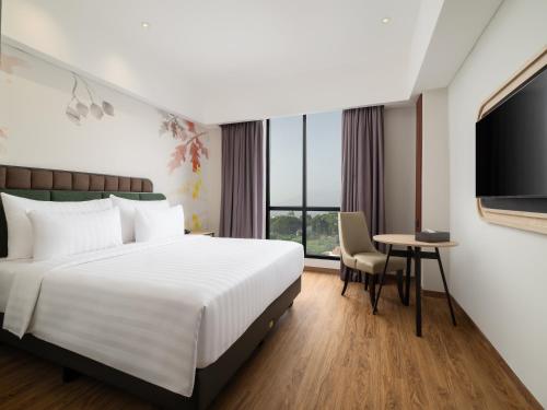 a hotel room with a bed and a tv at Luminor Hotel Padjadjaran Bogor by WH in Bogor