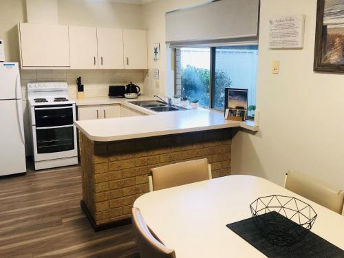 a kitchen with white cabinets and a table and a counter top at API Busselton Seaside Escape Apartments in Busselton