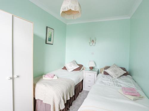 2 camas en una habitación con paredes azules en Bro Dawel, en Beaumaris