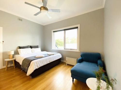 um quarto com uma cama e uma cadeira azul em The Gabby's Holiday House em Nuriootpa