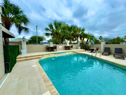 a swimming pool with chairs and tables and palm trees at Holiday Inn Express Hotel & Suites Tampa-Oldsmar by IHG in Oldsmar