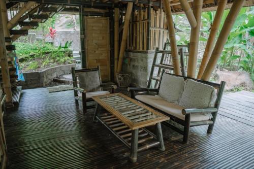 two chairs and a coffee table on a porch at Sun Sang Eco Retreats in Tabanan