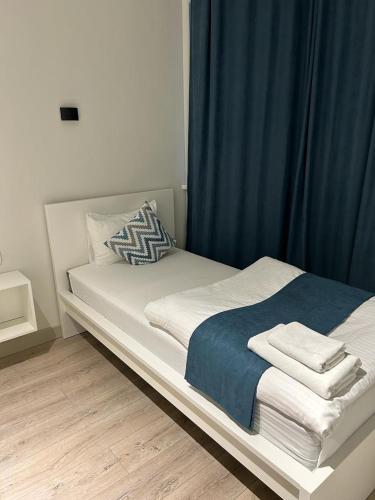 a white bed with blue curtains and towels on it at SB River Hotels in Atyraū