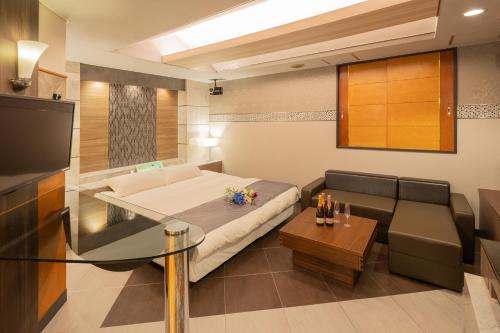 a room with a bed and a couch and a table at ホテル ブルジュア 久留米 Hotel Bvljua -レジャーホテル- in Kurume