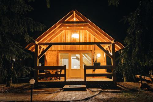 a wooden cabin with a large door at night at Ranczo Targówka in Malanów